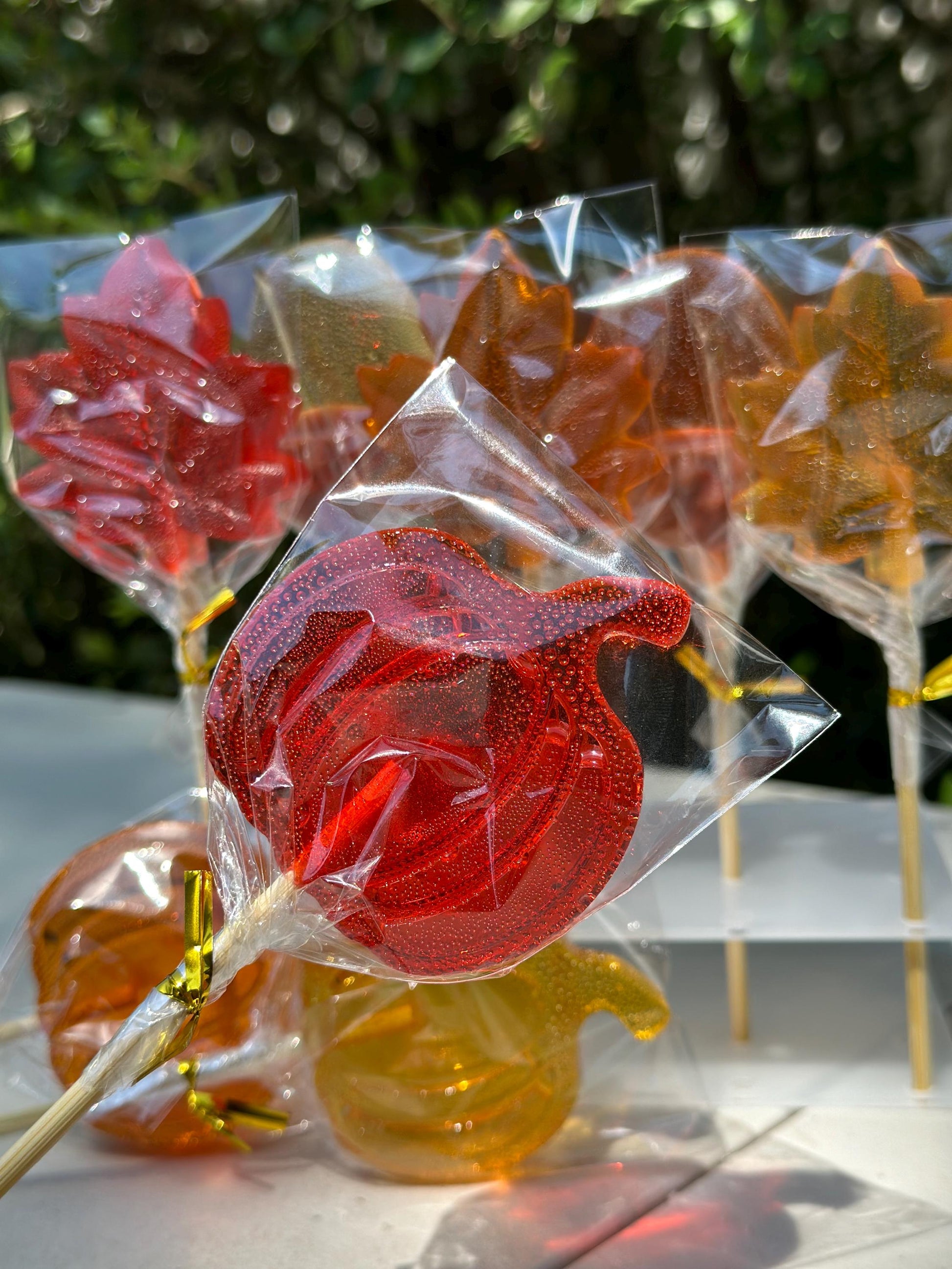 Fall lollipops in leaf and pumpkin shapes wrapped and tied with gold ribbon