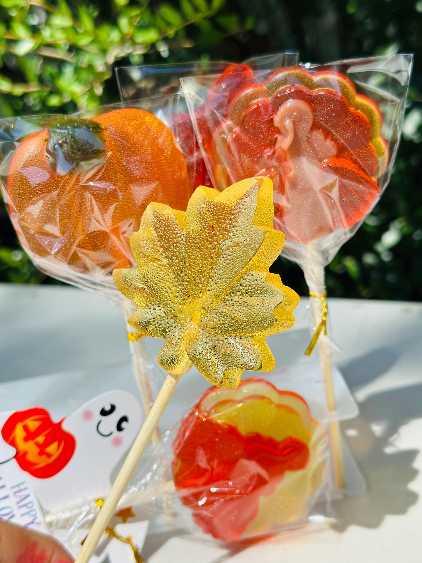 Assorted fall lollipops shaped like a pumpkin, a leaf and a turkey, tied with ribbon