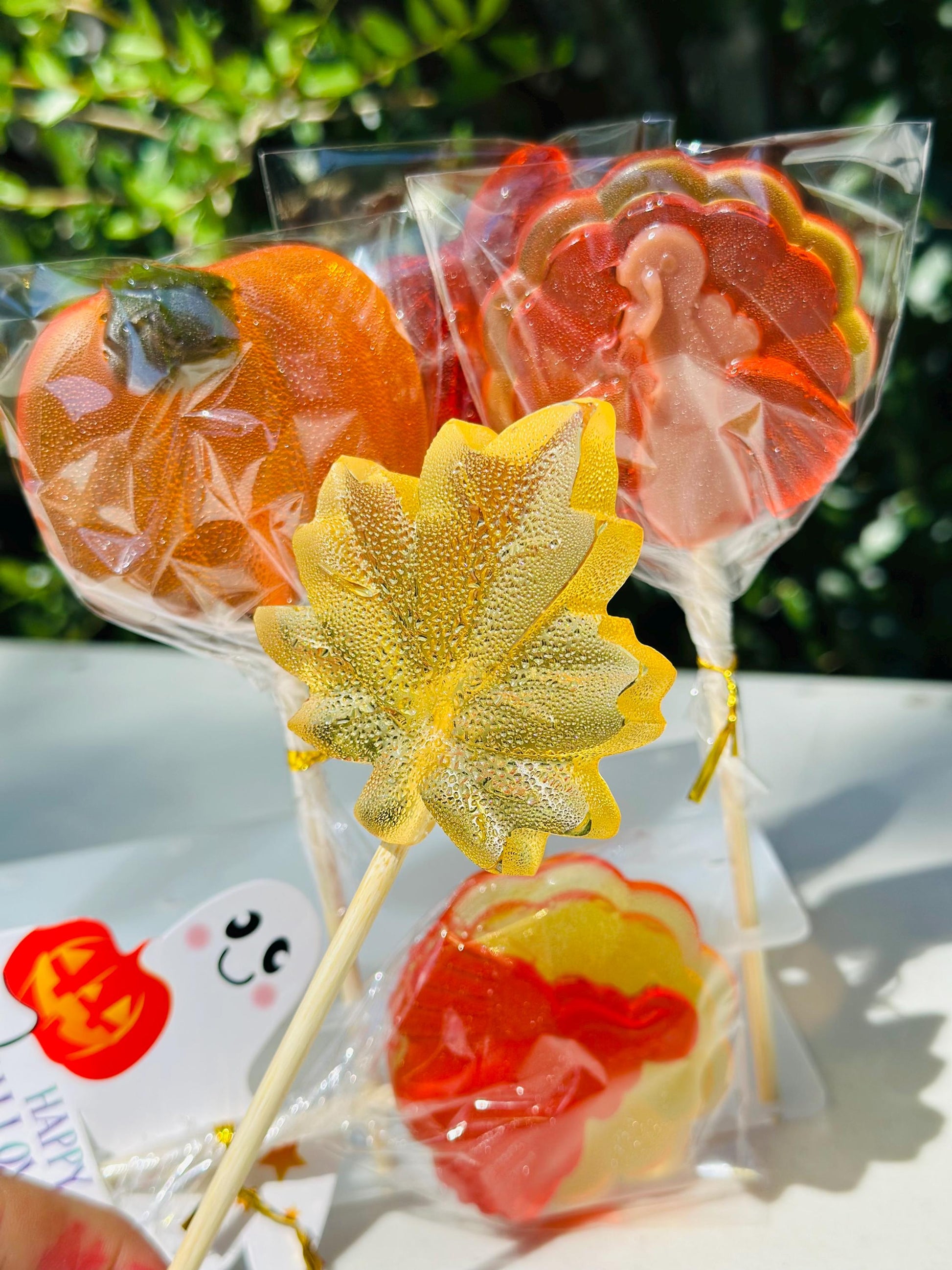 Assorted fall lollipops shaped like a pumpkin, a leaf and a turkey, tied with ribbon