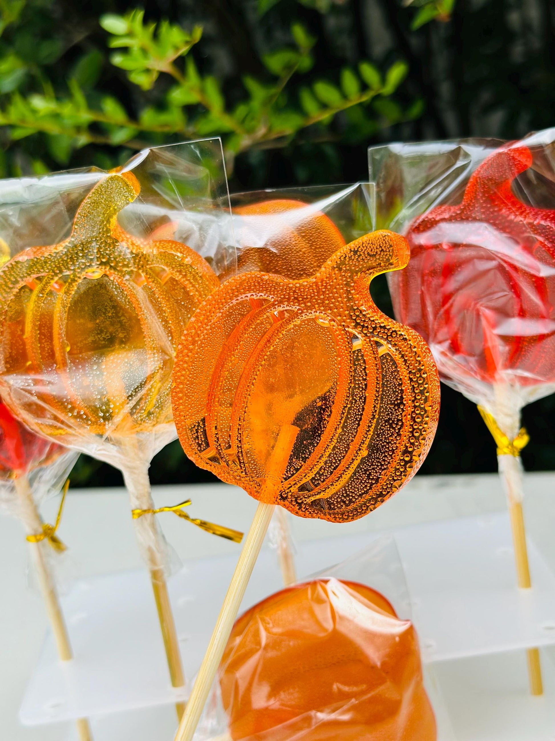 Orange and red pumpkin shaped lollipops on sticks, individually wrapped