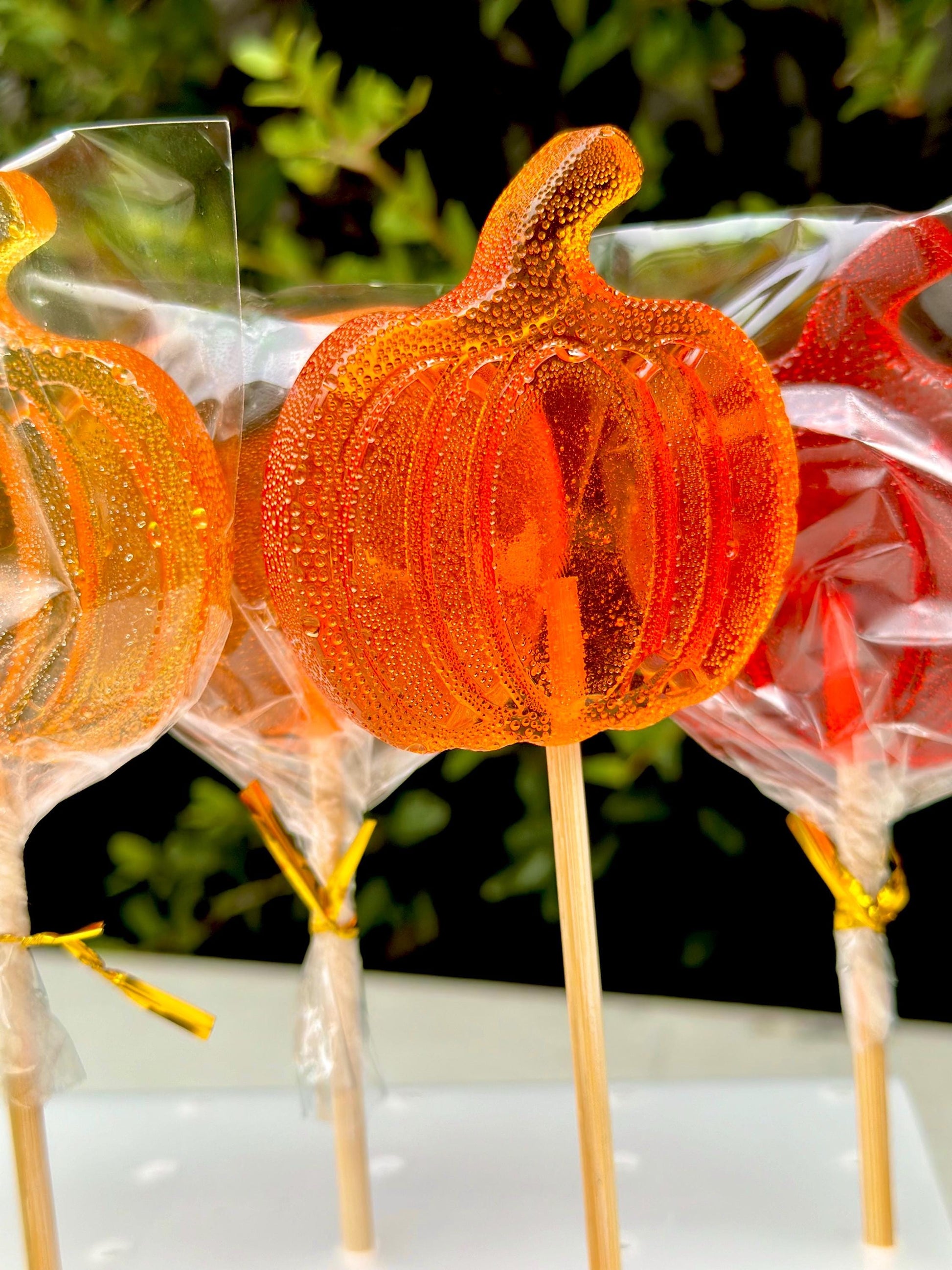 Close-up of handmade pumpkin lollipops with a glossy orange shine