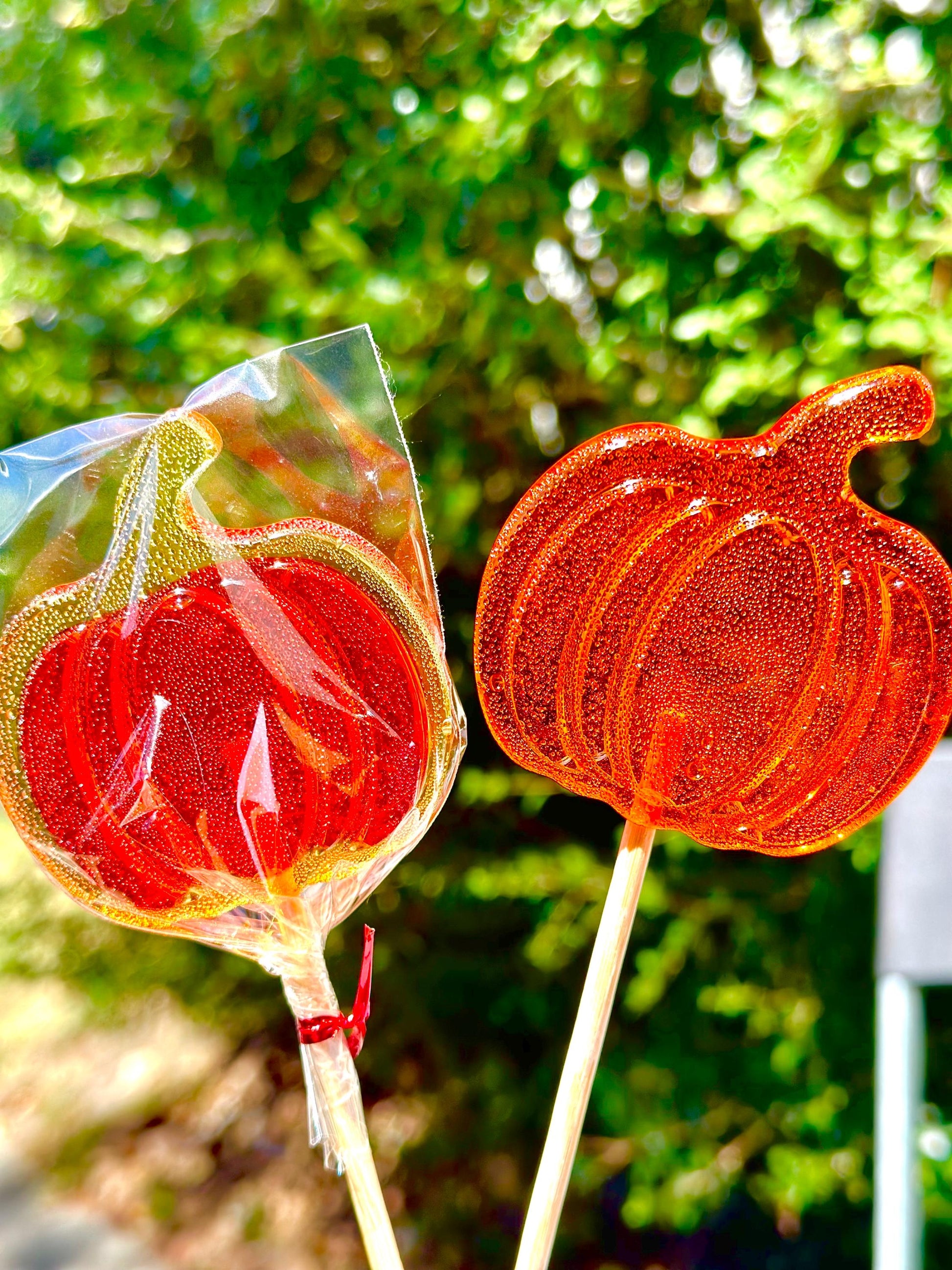 Two orange and red pumpkin lollipops on sticks