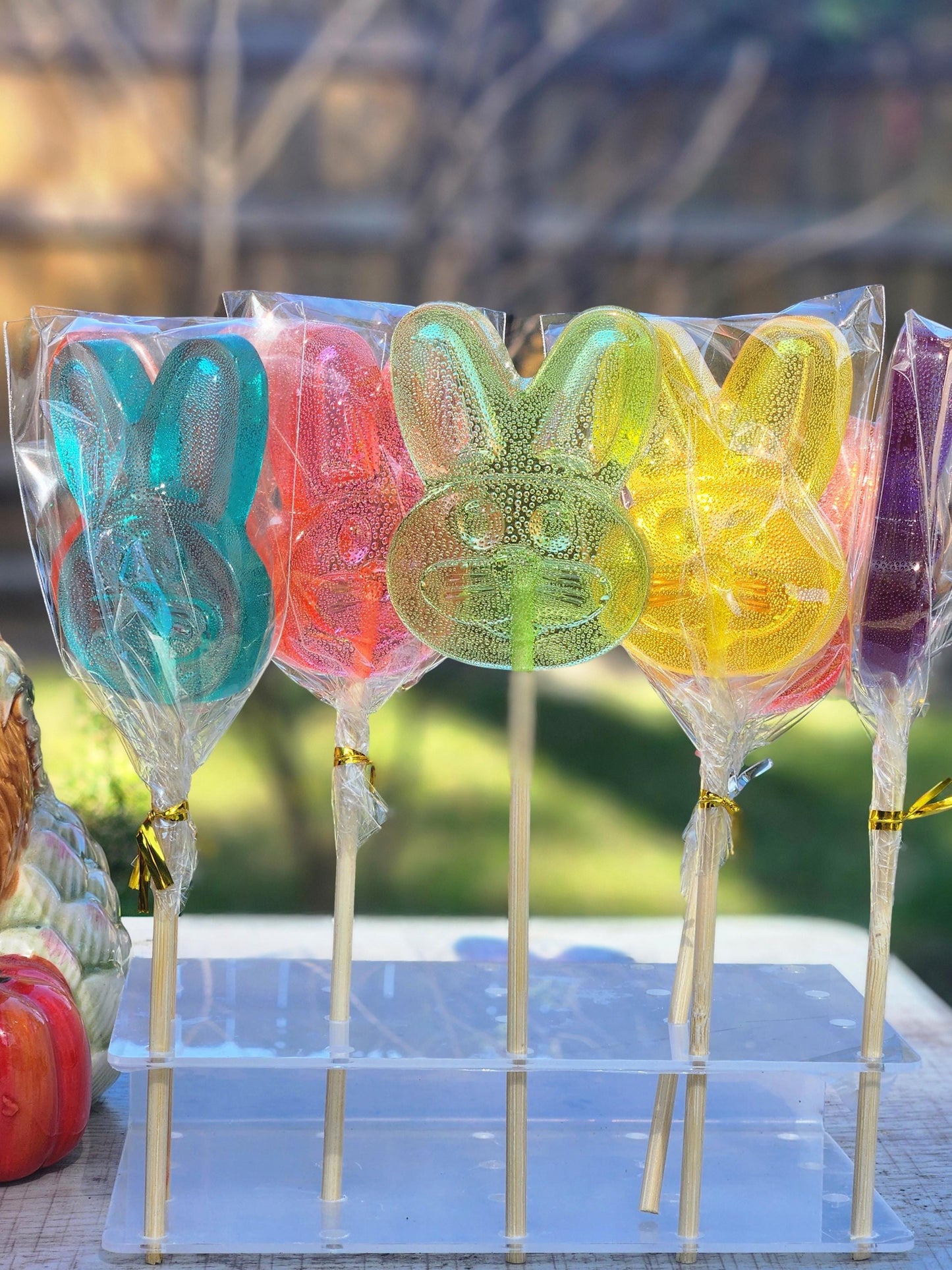 Bunny shaped lollipops in blue, green, yellow, orange and purple on a display stand